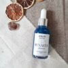 Frasco gotero con aceite color azul junto a tres rodajas de naranja y una amatista. Intencionado para trabajar con la luna nueva