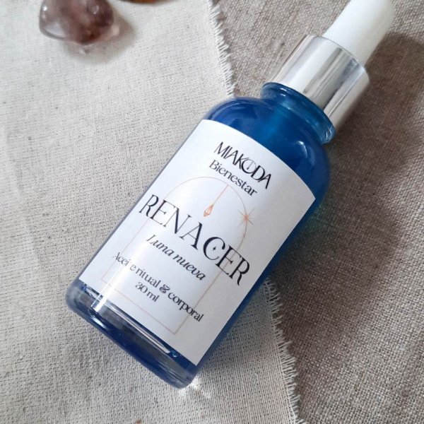 Frasco con aceite ritual Renacer, de color azul e intencionado para la luna nueva. Rodeado de rodajas de limón