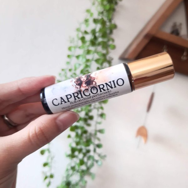 mano sosteniendo un roll on con tapa dorada del zodiaco