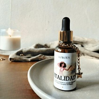 Frasco de aceite esencial Miakoda 'VITALIDAD' con etiqueta ilustrada, sobre plato de cerámica y vela encendida, estilo místico.